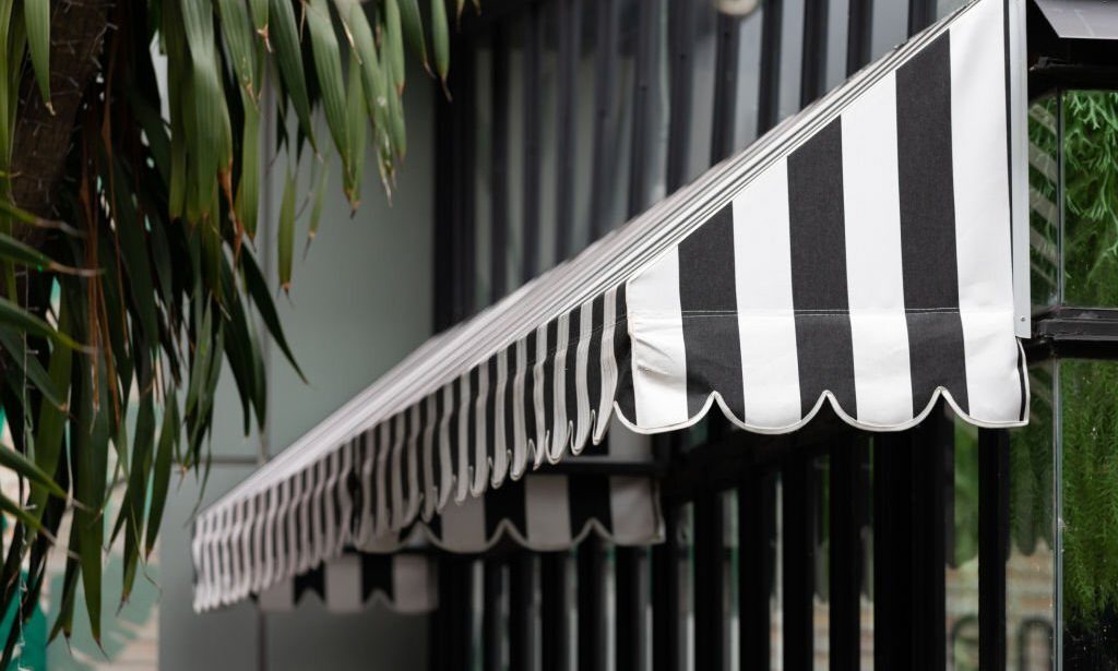 black and white striped awning over the shop window. canvas roof shading. exterior roof.